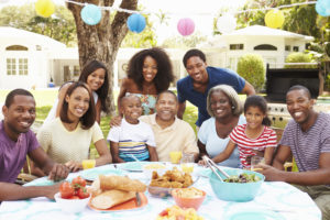 Multi Generation Family Enjoying Meal In Garden Together