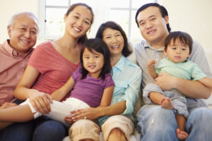 Multi Generation Family Sitting On Sofa At Home Together